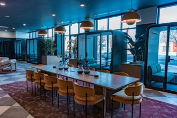 A long wooden table is surrounded by chairs in a room with a checkered floor.
